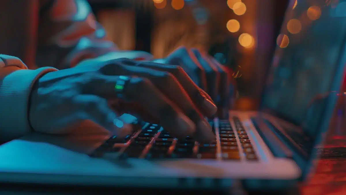 Closeup of hands typing a complex password on a laptop.